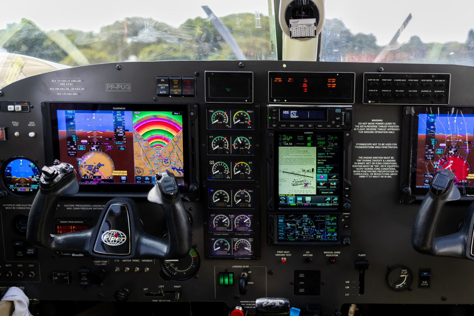 Vista frontal do painel com aviônicos Garmin e instrumentos de motor