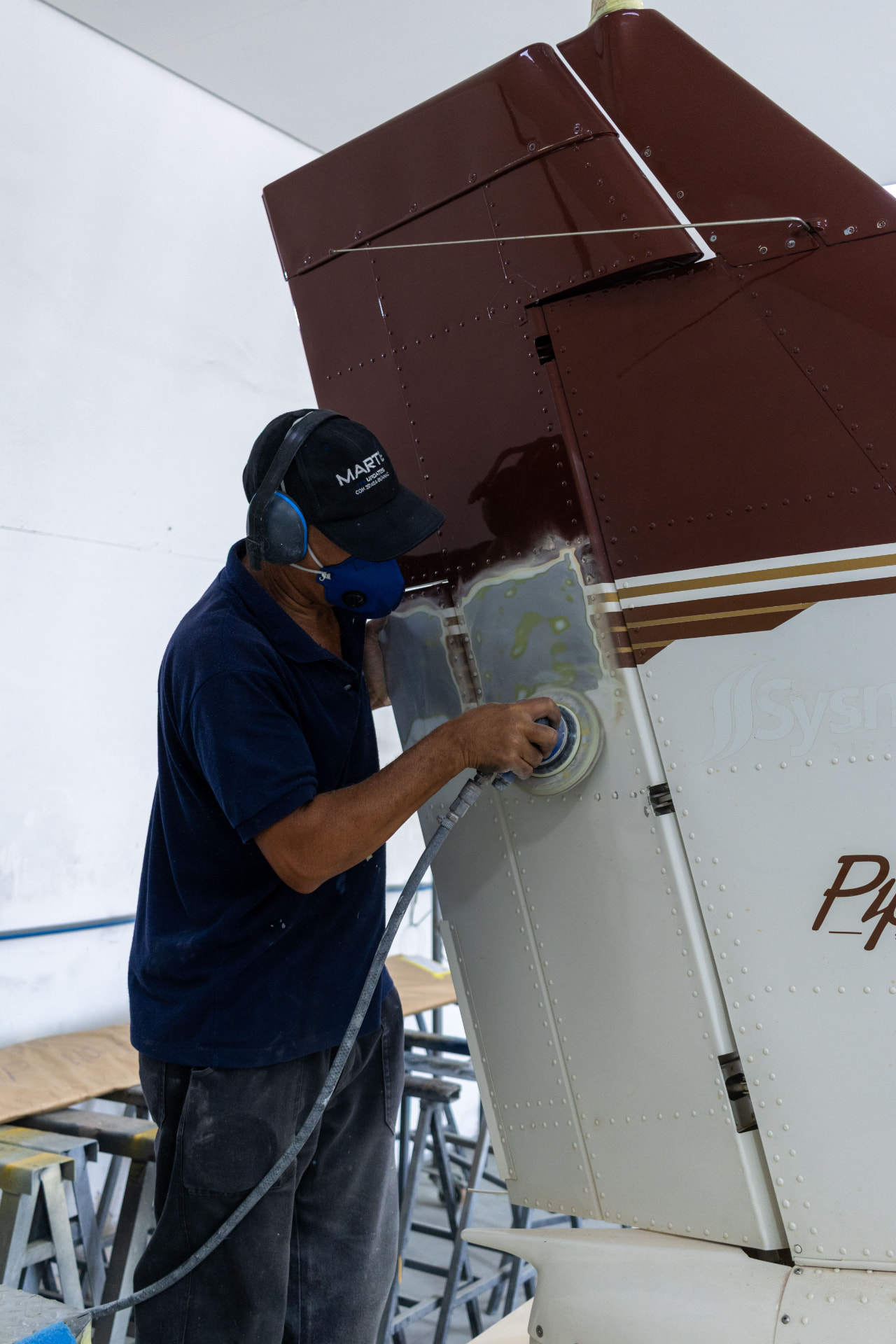 Técnico lixando a superfície da aeronave antes da pintura